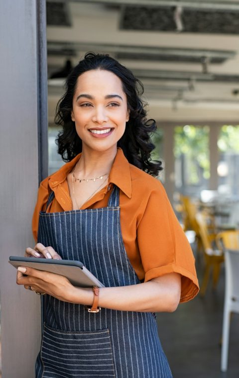 Small business entrepreneur at cafe entrance using digital tablet